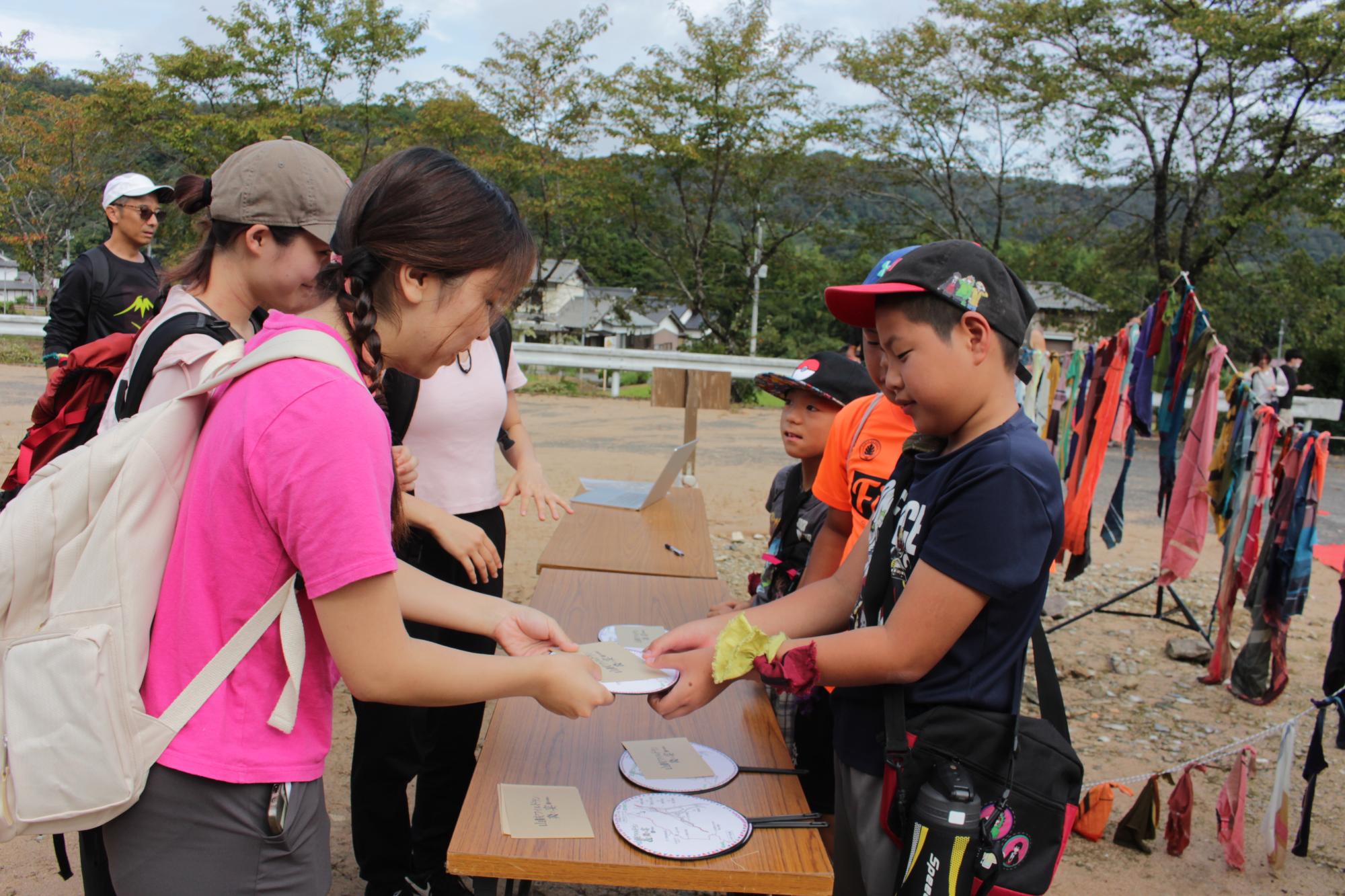 受付でミッションとマップを渡す小学生
