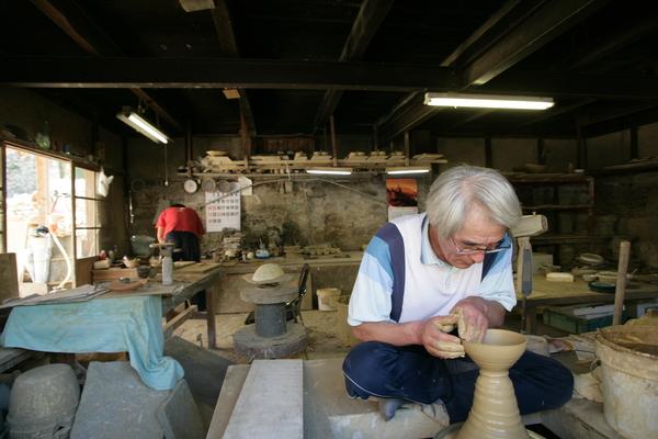 工房でろくろを回し陶芸品を作る職人の写真