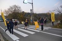 黄色い旗を持った大人が横断歩道で子供たちが安全にわたれるよう誘導している写真