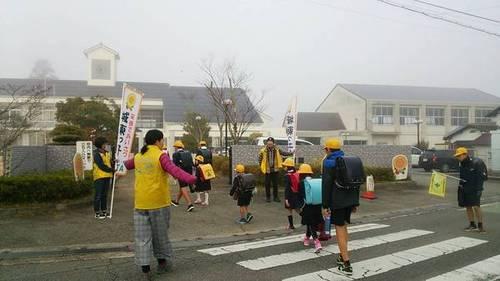 見守りを兼ねて学校へ向かう児童に挨拶をする黄色のベストを着用した地域の人・保護者・学校の先生達の写真