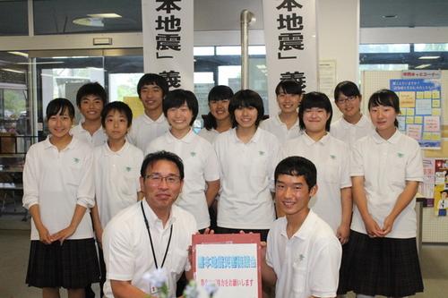 熊本地震災害義援金の募金箱を持ち、こちらに笑顔を向けている生徒達の写真