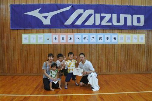 MIZUNOの横断幕と全日本ヘディス選手権と書かれた体育館の壁を背にした家族5人の写真