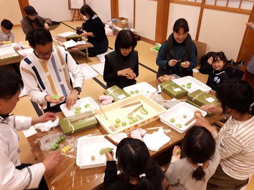 テーブルいっぱいに材料を広げみんなで和菓子を作っている様子の写真