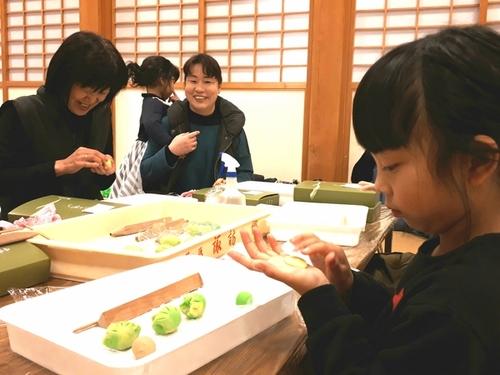 女の子が小さな手のひらの上で真剣な表情で和菓子を作っている様子の写真