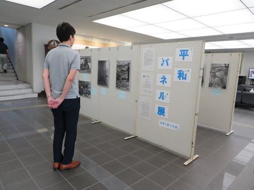 ボードに展示された平和パネル展の作品を観る男性の写真