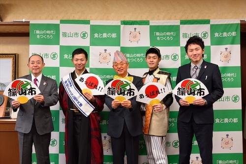 篠山市をPRする扇子を持って個性的な衣装に身を包んだ3名の男性と両端に立つスーツ姿の男性の写真