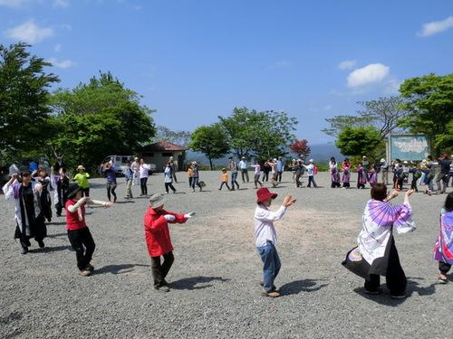 晴天の広場でたくさんの参加者が輪になってデカンショ踊りを踊る様子の写真