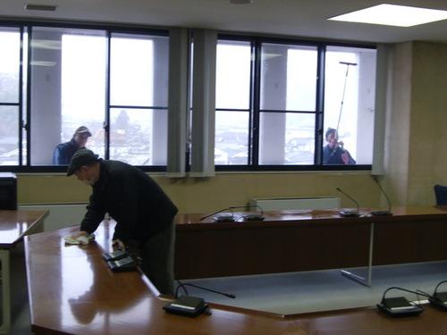 議会フロアの窓や机を掃除する三人の議員らの写真