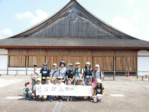 大きな蔵のような建物の前で「丹波篠山市へようこそ」の横断幕を掲げて撮った参加者の集合写真