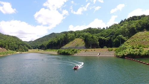 ダム湖の水上を旋回しながら走るボートの上方からの写真