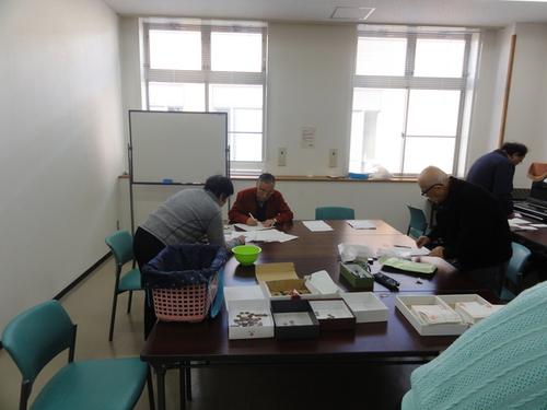 集まった書き損じハガキと一円玉の集計作業をする4名の篠山ユネスコ会員の写真