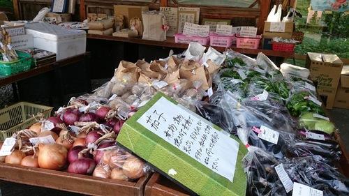 直売所で販売している茄子や玉ねぎなどの農産物が木箱にぎっしりと並ぶ様子の写真