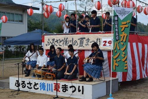 篠山鳳鳴高校のデカンショバンドメンバーがステージ上で太鼓や三味線、笛などで演奏を披露している様子の写真