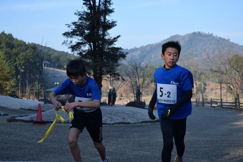 男子の部で優勝した多紀ランナーズジュニアAチーム所属の2区中川さんから3区西田さんへタスキがつながれたリレーの様子の写真