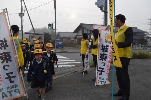 見守りを兼ねて通学児童に挨拶をする黄色のベストを着用した地域の人・保護者・学校の先生達の写真