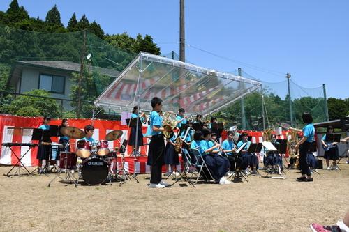 紅白幕のステージでブルーのシャツを着た丹波中学校の生徒たちによる吹奏楽演奏の写真