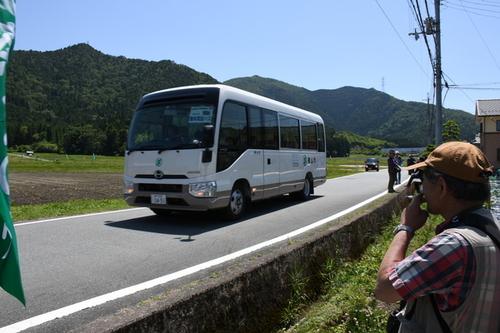 山あいの道を来場者を乗せて走る無料周回バスの写真