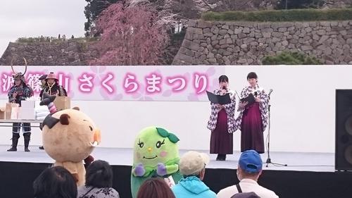 丹波篠山さくらまつりと書かれたステージの上でステージの司会進行をするはかま姿の観光大使のお二人の写真