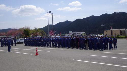 晴天の日の福祉センター前の駐車場に整列し訓練に取り組む篠山市消防団員の写真