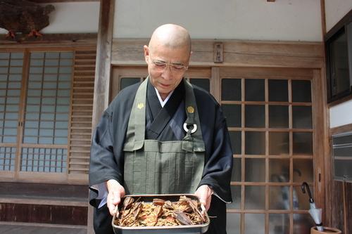奥県守の法円寺の住職の原彰道さんがササユリの種を見せている写真