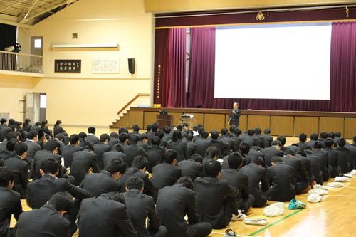 体育館の床に座り講座を聞く篠山産業高等学校の生徒たちの写真