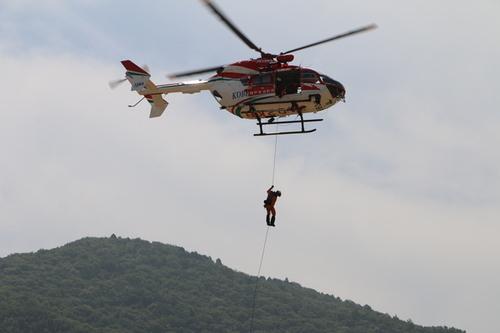 ヘリコプターから一本のロープで消防隊員が降りてくる様子の写真