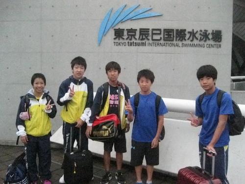 東京辰巳国際水泳場の前でジュニア水泳大会に出場したメンバーがピースサインをしている写真