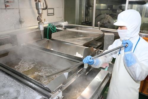ケンミン食品の従業員が大きな釜で黒枝豆を茹でている様子の写真