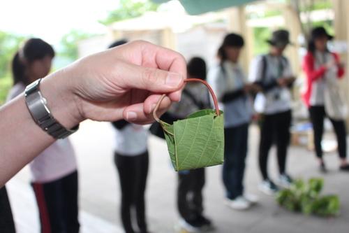 草花で作った小さなバッグを手に持ってかかげている写真