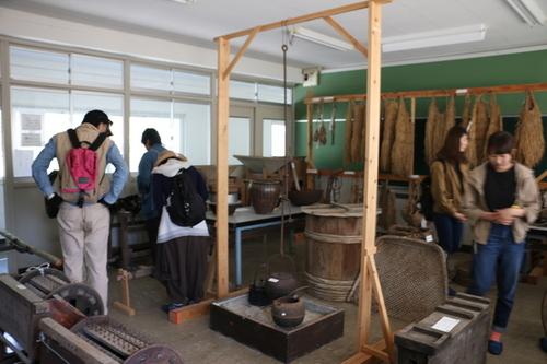 教室内に展示された昔ながらの農機具や道具などを興味深そうに見学する参加者の方々の写真