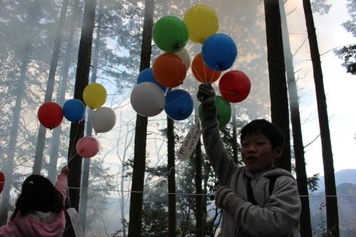 子どもたちが山の中で風船を持っている写真