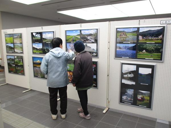 市民ホールで展示中の応募作品を見ている2人の男女の写真