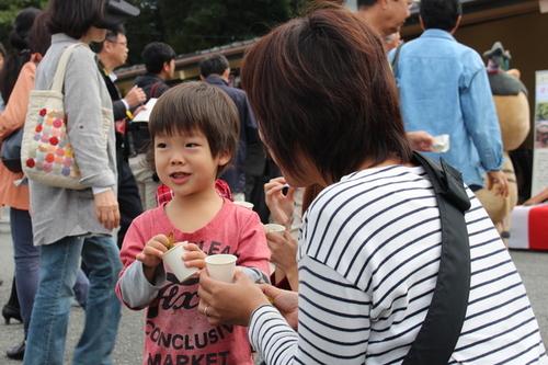 ふるまわれた黒枝豆を食べる来場者の女性と男の子の写真