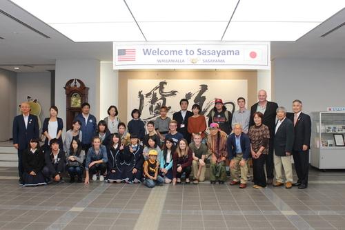 「Welcome to Sasayama」と書かれた横断幕のもとで記念撮影をするワラワラ市の学生とホストファミリーの集合写真