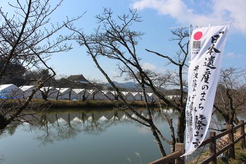 「日本遺産のまち」というのぼり旗の向こうに見える穏やかな川の写真
