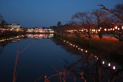 夜の篠山城跡周辺でぼんぼりが遠くまで並び水辺に反射する幻想的な風景の写真