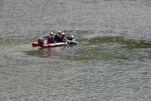 ダム湖からボートへ訓練用人形を引き上げる消防官らの写真