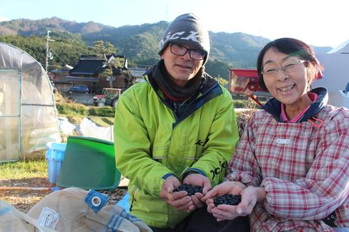 黒豆を両手に持つ黒豆農家の男性と女性の写真