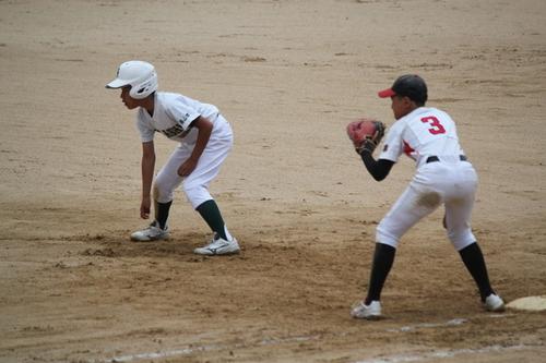 ベースを守る相手方の選手とリードし様子をうかがう篠山東野球少年団の選手の写真