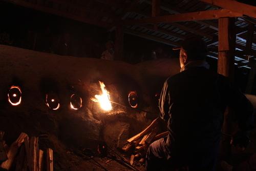 夜間の暗闇の中で焼成を行う方が窯の炎に照らされて浮かび上がる後ろ姿の写真