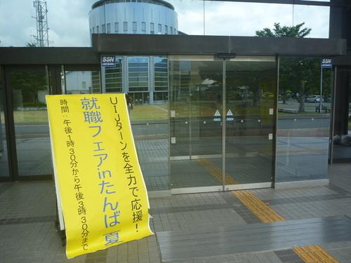 「UIJターンを全力で応援!就職フェアinたんば夏」と書かれた黄色い布の看板が置かれた建物入口の写真