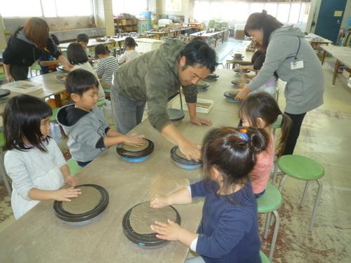 講師の清水さんが子どもたちに粘土のこね方を教えている様子の写真