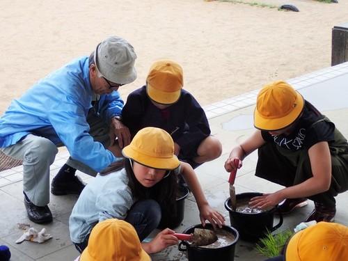 黄色い帽子を被った生徒たちに指導をする講師の堀江溢雄さんの写真