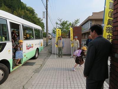 城南小学校に通う子供たちが通学バスから降りて学校の門をくぐる写真