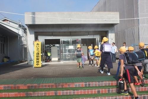 あいさつ運動の看板と黄色帽子の登校してくる生徒の写真