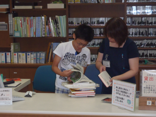 子どもと図書館の人が本を見ている写真
