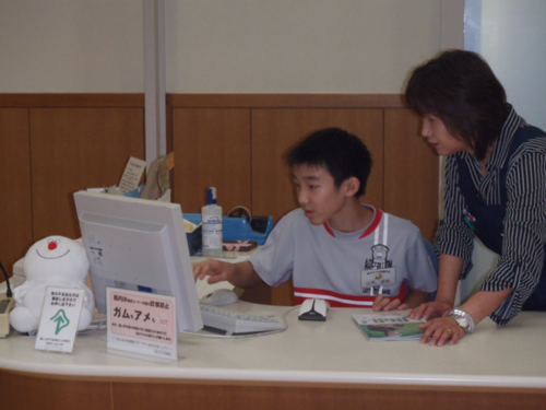 子どもが図書館の人とパソコンを使っている写真