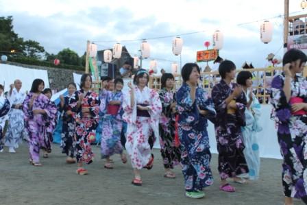 浴衣姿の女性が舞台の周りで踊っている写真