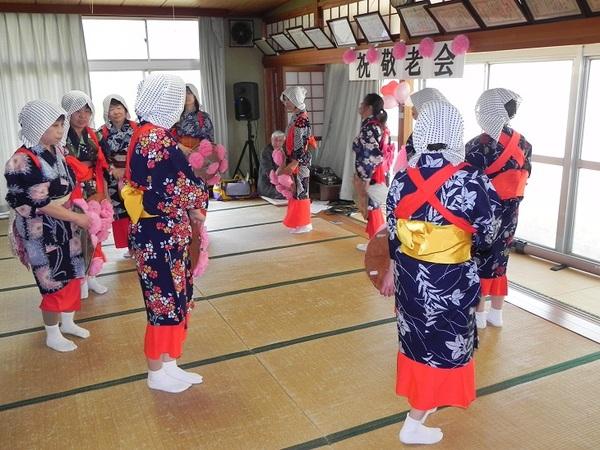 紺に花柄の入った浴衣を着て頭には水玉の手ぬぐいをつけみんなで輪になって踊っている写真