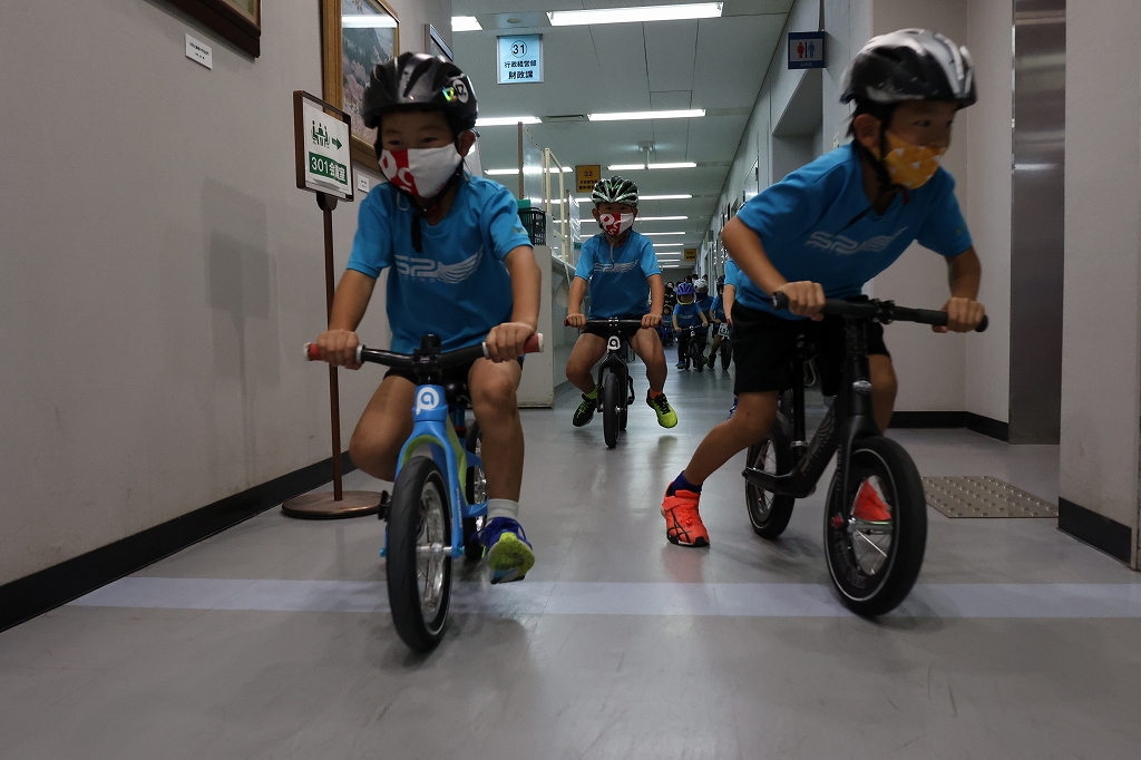 市役所の廊下をペダルのない自転車で走るこども